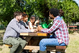 Friends talking at an outdoor community garden table (illustrative stock photograph)