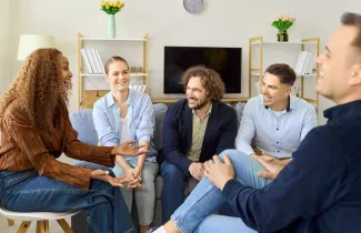 Adults sharing conversation in a living room (illustrative stock photograph)