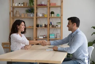 A woman and man greeting each other across a table (illustrative stock photograph)